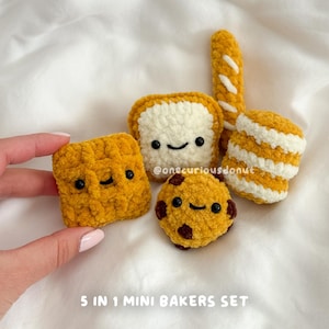 Puede incluir: Un conjunto de cinco miniaturas de productos de panadería de ganchillo, que incluyen un gofre, una rebanada de pan, una baguette, una galleta y un pastel en capas. Cada artículo es amarillo y blanco con caras sonrientes. El texto "5 IN 1 MINI BAKERS SET" está en la parte inferior.