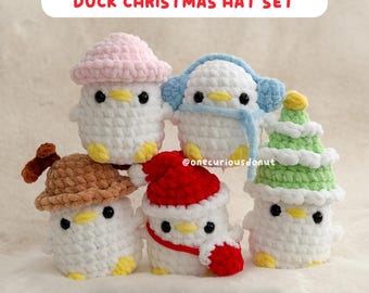 May include: A set of five white crochet duck figures, each wearing a different hat or head covering. The hats include a pink beanie, blue earmuffs, a brown hat, a red Santa hat, and a green Christmas tree hat. The text "DUCK CHRISTMAS HAT SET" and "CROCHET PDF PATTERN" are displayed.