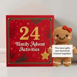 May include: A red box with gold lettering that reads "24 Family Advent Activities" next to a crocheted gingerbread person holding a sign that says "The best gifts are moments shared together."