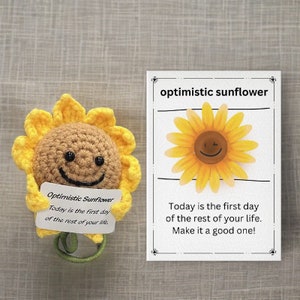 Lachende zonnebloem met optimistische boodschap, schattige wollen pop met wenskaart, positieve sfeer, vrolijkheid, lachende gebreide zonnebloempop