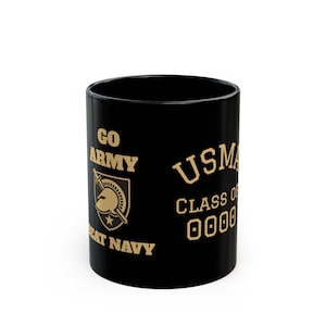 Peut inclure: Mug en céramique noire avec texte et graphiques dorés. Le mug présente les mots "GO ARMY", "USMA" et "GREAT NAVY". Un bouclier avec un casque et une étoile est également visible. Le texte "CLASS OF 0000" est également imprimé.