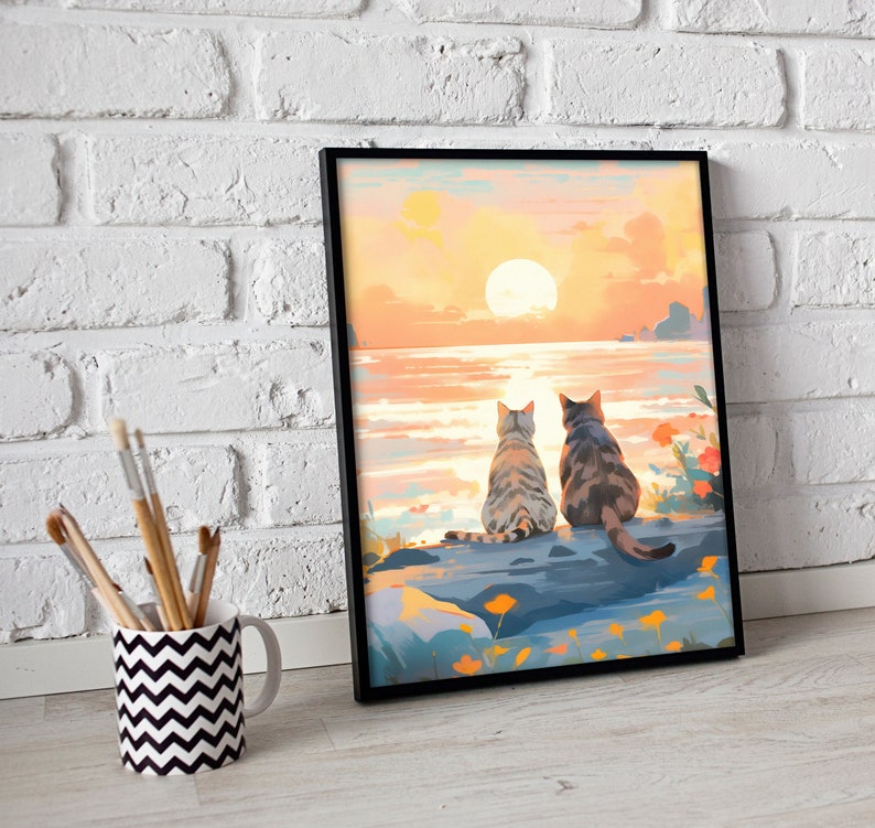 May include: Two cats sit side-by-side on a rock overlooking a body of water with a large orange sun setting in the distance. The sky is a gradient of orange, pink, and yellow.