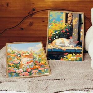 May include: Two framed paintings of cats in a field of flowers. The first painting shows a white cat sleeping on a wooden porch with a window behind it. The second painting shows an orange cat sitting in a field of flowers.