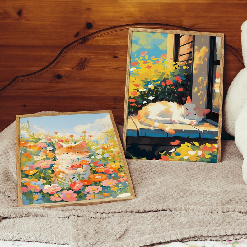 May include: Two framed paintings of cats in a field of flowers. The first painting shows a white cat sleeping on a wooden porch with a window behind it. The second painting shows an orange cat sitting in a field of flowers.