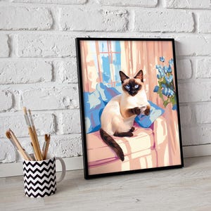 May include: Framed art print of a Siamese cat with blue eyes, sitting on a pink couch with blue pillows. The cat is holding a small cup. The background features a window and blue flowers.