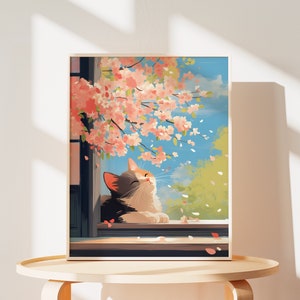 May include: A framed art print depicting a calico cat resting on a windowsill beneath a blooming cherry blossom tree. Pink petals drift through the air against a bright blue sky, with green foliage visible in the background and dark window frames.