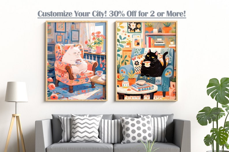 May include: Two framed illustrations of cats sitting in armchairs, each holding a cup. The cat on the left is white and the cat on the right is black. Both cats are sitting in floral patterned armchairs. The illustrations are set against a white wall.