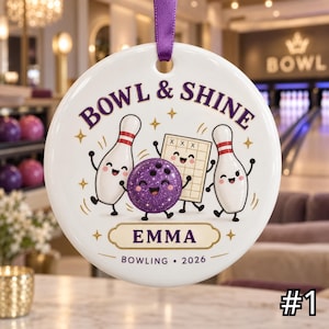 May include: A round white ceramic ornament with a purple ribbon, featuring a purple glitter bowling ball, two bowling pins, and a scorecard. The text reads BOWL & SHINE, EMMA, and BOWLING 2026. The design includes gold star accents and a gold border.