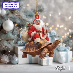 May include: A Christmas ornament featuring Santa Claus riding a large tortoise. Santa is dressed in a red suit and hat, holding a candy cane and a sack of gifts. The ornament has a gold string for hanging.