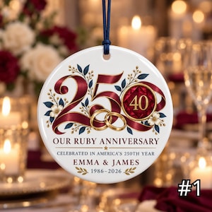 May include: A round white ceramic ornament hanging from a dark blue cord. The design features a large burgundy number 250, two gold rings, and floral accents. Text reads: OUR RUBY ANNIVERSARY, CELEBRATED IN AMERICA'S 250TH YEAR, EMMA & JAMES, 1986-2026.