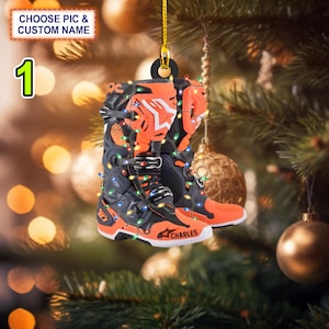 May include: Orange and black motocross boots with a personalised name "CHARLES" on the side, decorated with colourful Christmas lights, hanging from a Christmas tree.