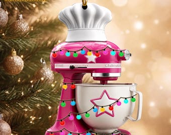 May include: A pink stand mixer ornament topped with a white chef hat, featuring a white mixing bowl with a star cutout, decorated with a string of colorful Christmas lights and a white star, with the text NAME CAN BE CHANGED visible at the top.