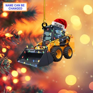 May include: Yellow toy construction vehicle with a red Santa hat and the name "Lucas" on it. The vehicle is decorated with colorful Christmas lights.