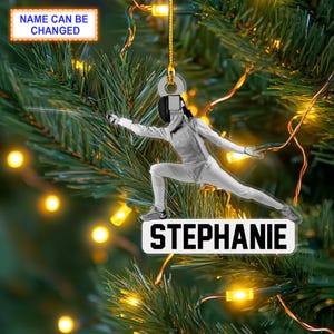 May include: A Christmas ornament featuring a silhouette of a person fencing, with the name "Stephanie" printed on the bottom.