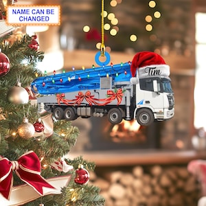 May include: A white concrete pump truck with a blue tarp and Christmas lights. The truck is wearing a red Santa hat with the name "Tim" written on it. This is a Christmas ornament.