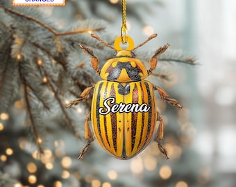 May include: A beetle-shaped ornament with a yellow and black striped body, the name "Serena" in white script, and a gold hanging string. The text "Name Can Be Changed" and "Style 1" are also visible on the ornament.
