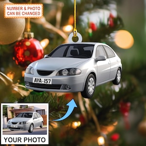 May include: Silver car ornament with a license plate that reads AYA-157. The ornament hangs from a gold string against a blurred Christmas tree background. The text "NUMBER & PHOTO CAN BE CHANGED" is at the top.