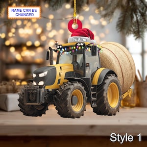 Op de afbeelding: Geel en zwarte tractor kerstversiering met een kerstmuts en lichtslingers. De tractor heeft een hooibaal en de tekst "Custom" op de hoed. De tekst "Name Can Be Changed" is ook zichtbaar.