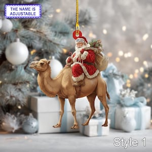 May include: A festive Christmas tree decoration showing Santa Claus on a camel. Santa wears a red suit with white fur trim and carries a sack. The ornament has a gold hanging string and the text "THE NAME IS ADJUSTABLE" and "Style 1".