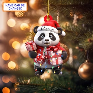 Könnte beinhalten: Ein Weihnachtsbaumschmuck mit einem Panda, der einen Weihnachtsmann-Hut trägt und Geschenke hält. Der Panda ist von bunten Weihnachtslichtern umgeben. Der Schmuck trägt den Namen "Cherrrie".