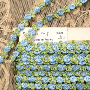 Op de afbeelding: Een close-up van een blauw en groen bloemenband. Het lint is gemaakt in Frankrijk en is gelabeld met het nummer "700", "Col. 8" en "Quant. 100".