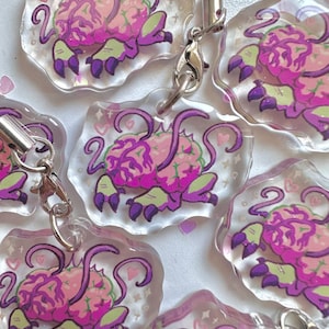 Op de afbeelding: Vijf roze en paarse breloques in de vorm van een brein met glitter en harten op een transparante achtergrond. Elke breloque heeft een zilveren lus om aan een sleutelhanger of tas te bevestigen.