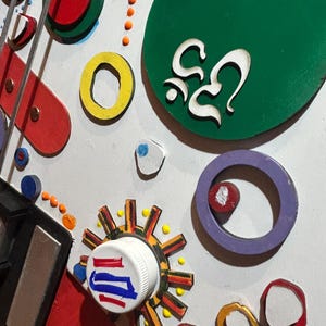 Może przedstawiać: Zbliżenie kolorowego, abstrakcyjnego dzieła sztuki z mieszanką kształt&oacute;w i kolor&oacute;w. Dzieło zawiera okręgi, pierścienie i inne formy geometryczne w kolorze czerwonym, ż&oacute;łtym, zielonym i niebieskim. Dzieło ma kapryśną, zabawną estetykę.