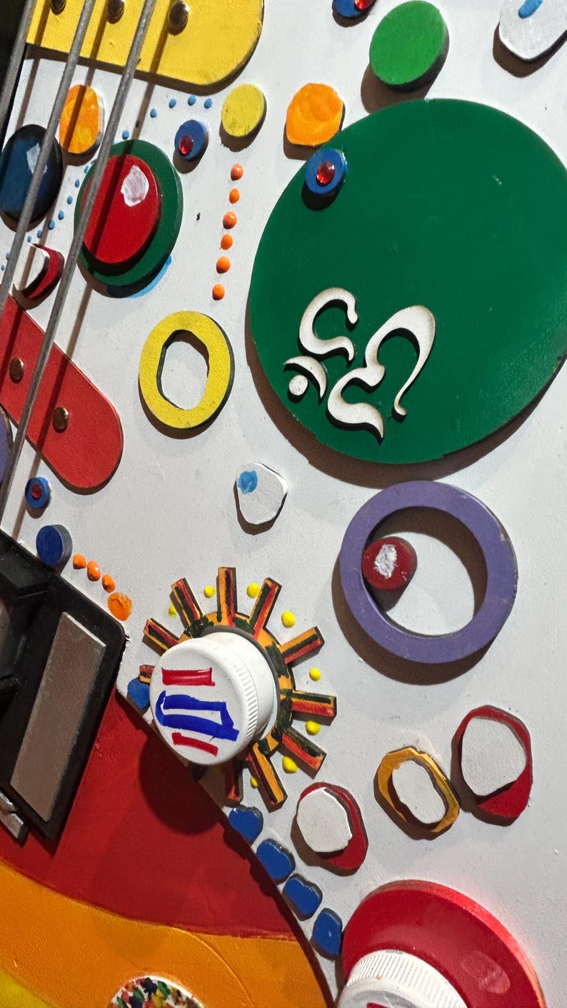 Może przedstawiać: Zbliżenie kolorowego, abstrakcyjnego dzieła sztuki z mieszanką kształt&oacute;w i kolor&oacute;w. Dzieło zawiera okręgi, pierścienie i inne formy geometryczne w kolorze czerwonym, ż&oacute;łtym, zielonym i niebieskim. Dzieło ma kapryśną, zabawną estetykę.