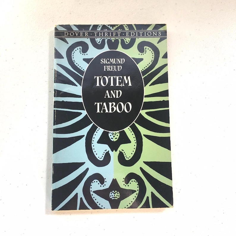 May include: A black and white book with a green and blue patterned cover. The title is "Totem and Taboo" by Sigmund Freud. The book is part of the Dover Thrift Editions series.