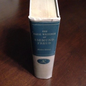 May include: A blue and white book with the title "The Basic Writings of Sigmund Freud" on the spine. The book is part of the Modern Library series.