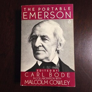 May include: A red book with the title "The Portable Emerson" and the author "Edited by Carl Bode in collaboration with Malcolm Cowley". A black and white portrait of a man with white hair and a beard is on the cover.