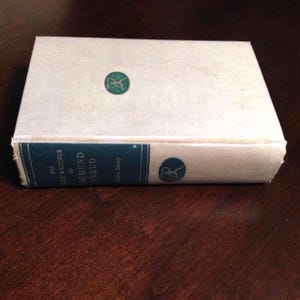 May include: A white book with a blue spine. The spine has the text "The Basic Writings of Sigmund Freud" and a small logo. The book is on a wooden surface.