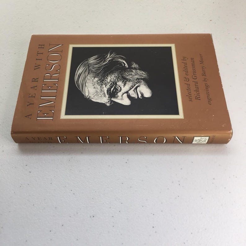 May include: A Year With Emerson book cover with a brown background and a black and white illustration of Ralph Waldo Emerson. The text on the cover reads "A Year With Emerson" and "selected & edited by Richard Grossman".