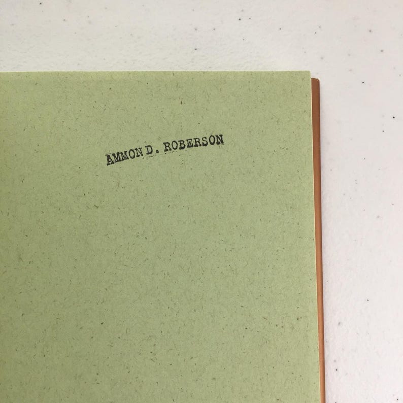 May include: A green book with the name "AMMON D. ROBERSON" printed on the cover.