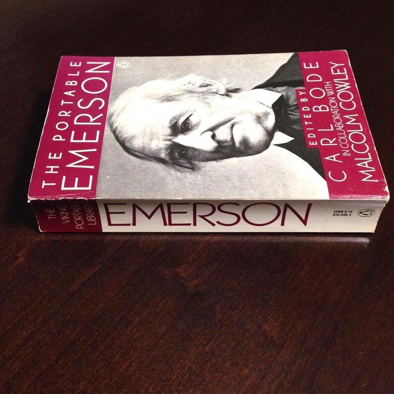 May include: A white book with a red spine titled "The Portable Emerson" by Ralph Waldo Emerson. The book is part of the Viking Portable Library series and is edited by Carl Bode in collaboration with Malcolm Cowley.