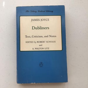 May include: A blue book with the title "Dubliners" by James Joyce. The book is part of The Viking Critical Library series and is edited by Robert Scholes and A. Walton Litz.