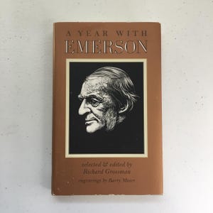 May include: A brown book titled "A Year With Emerson" with a black and white illustration of a man's face on the cover. The book is by Richard Grossman and has engravings by Barry Moser.