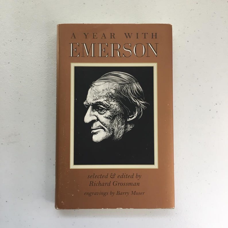 May include: A brown book titled "A Year With Emerson" with a black and white illustration of a man's face on the cover. The book is by Richard Grossman and has engravings by Barry Moser.