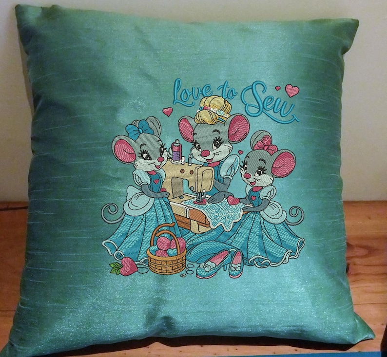 May include: A teal blue pillow with embroidered mice sewing on a sewing machine. The pillow has the text "Love to Sew" embroidered on it.