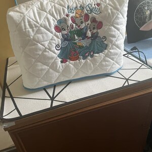 May include: White quilted sewing machine cover with embroidered mice and the text "Love to Sew".