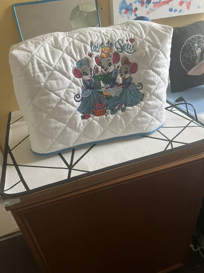 May include: White quilted sewing machine cover with embroidered mice and the text "Love to Sew".