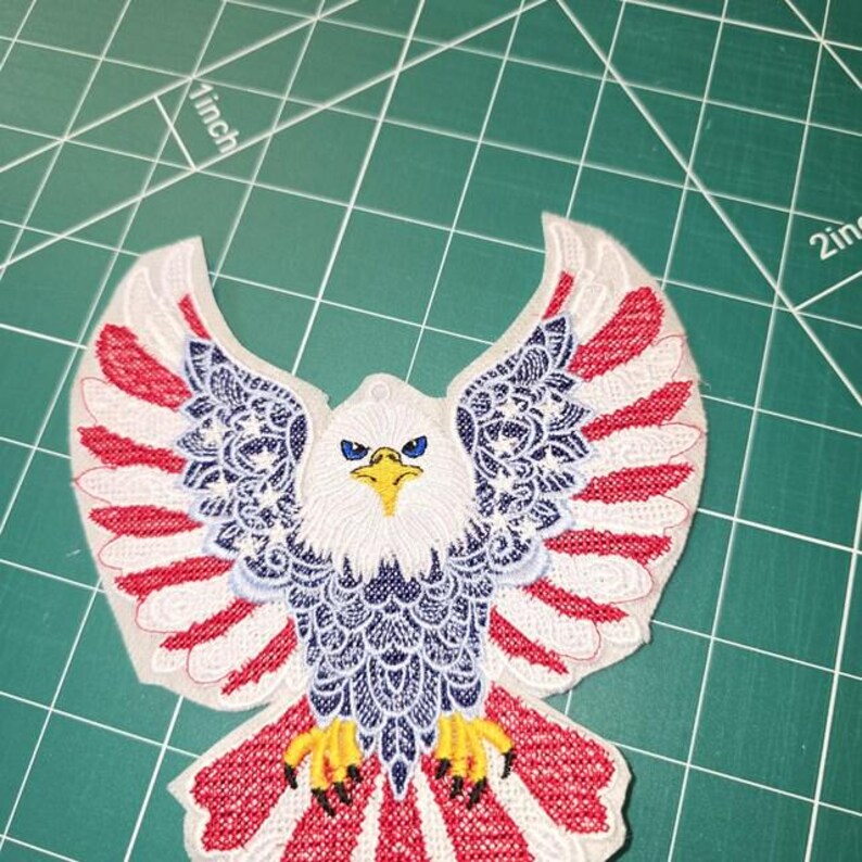 Puede incluir: Un parche bordado que muestra un &aacute;guila calva con las alas extendidas. El &aacute;guila tiene cabeza blanca, pico amarillo y ojos azules. Las alas y la cola muestran un patr&oacute;n rojo, blanco y azul con motivos de estrellas. El parche mide m&aacute;s de 5 cm.