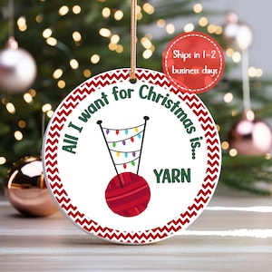 A knitting Christmas ornament is shown in front of a Christmas tree.  The crochet Christmas ornament says All I want for Christmas is... YARN.