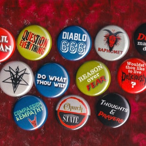 May include: A collection of 12 round button pins with various designs and slogans. The pins feature a variety of colors, including red, yellow, blue, green, and black. Some of the slogans include "Hail Satan", "Question Everything", "Diablo 666", "Do What Thou Wilt", "Reason Over Fear", "The Devil Made Me Do It", "Wouldst Thou Like To Live Deliciously", "Compassion & Empathy", "Church State", and "Thoughts & Prayers".