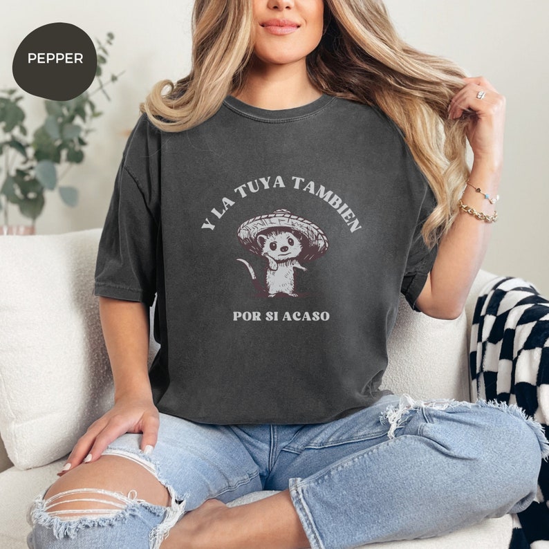 Pode incluir: Uma camiseta cinza escura com um rato de desenho animado usando um sombrero. O texto na camiseta diz "Y la tuya tambien por si acaso".