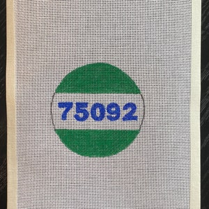 Può includere: Una tela bianca con un cerchio verde e blu che contiene il numero "75092".