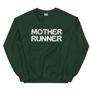 Può includere: Felpa verde scuro con la scritta bianca "MOTHER RUNNER" stampata sul davanti. La felpa ha un girocollo e maniche lunghe. Il tessuto sembra essere un materiale morbido e confortevole.
