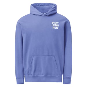 May include: A periwinkle blue hoodie with a front pocket and a hood. The text "POST LONG RUN" is printed in white on the upper chest area. The hoodie is made of a soft material.