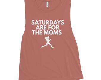 Puede incluir: Una camiseta sin mangas de color rosa polvoriento con el texto blanco SATURDAYS ARE FOR THE MOMS impreso en una fuente sans-serif en negrita, acompañado de una silueta gráfica blanca de una persona corriendo en el centro del pecho.