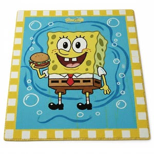 May include: A rectangular rug featuring a cartoon image of SpongeBob SquarePants holding a burger. The rug has a blue background with white bubbles and a yellow and white checkered border. The word "SPONGEBOB" is at the top.